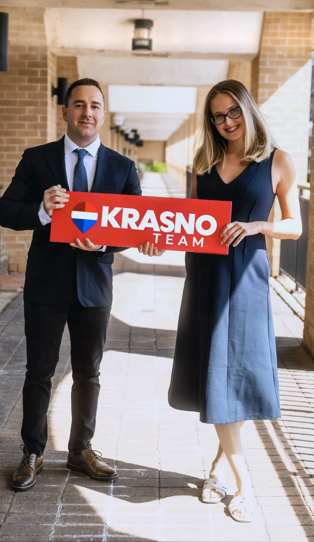 Anthony Krasno and Ana Yakovleva of the Krasno Team holding a Krasno Team sign